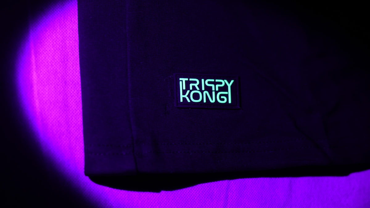 TrippyKong signature hem patch glowing cyan under purple UV light.